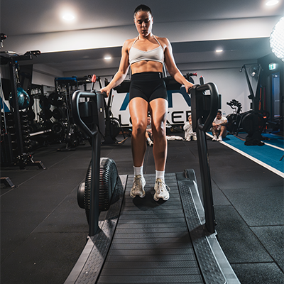 Lifestyle image of a model using the STEPR TreadSled XL for backward walking.