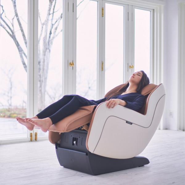 User relaxing in beige Synca CirC+ Massage Chair near window