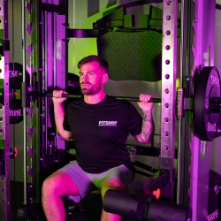 A person performing a seated shoulder press on the Taurus MS60 Elite Trainer in a gym.