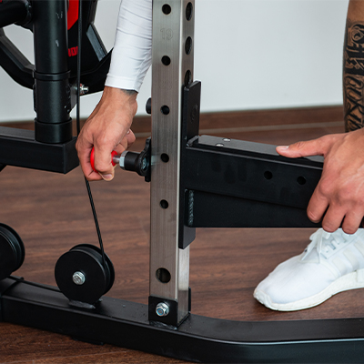 Close-up of user adjusting the safety arm on the Taurus MS20 Pro Plate Complete Trainer.