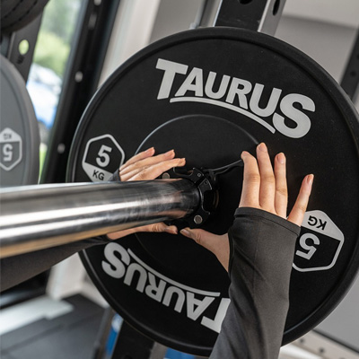 Image of a model placing the Taurus Olympic Magnetic Collar onto a barbell