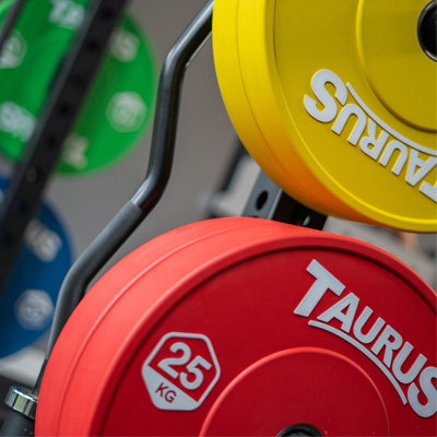 A close up of the Taurus Coloured Bumper Olympic Weight Plates mounted on a rack.
