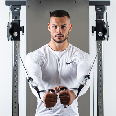 Lifestyle image of a model using the Taurus Design Line Dual Pulley for a cable fly exercise. 