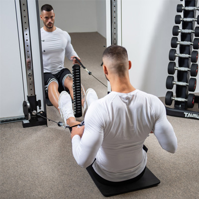 Lifestyle image of a model using the Taurus Design Line Dual Pulley for a low row exercise. 