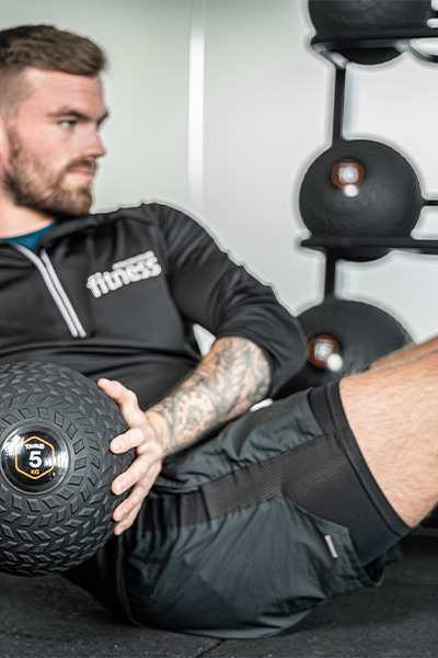User exercising with 5 kg slam ball with rack in background