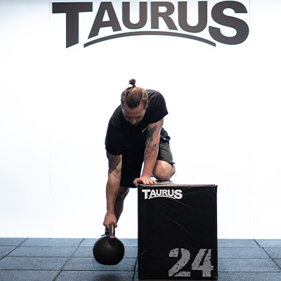 Image of a model performing a bent-over row with the 3-in-1 Plyo Box and a Taurus Kettlebell