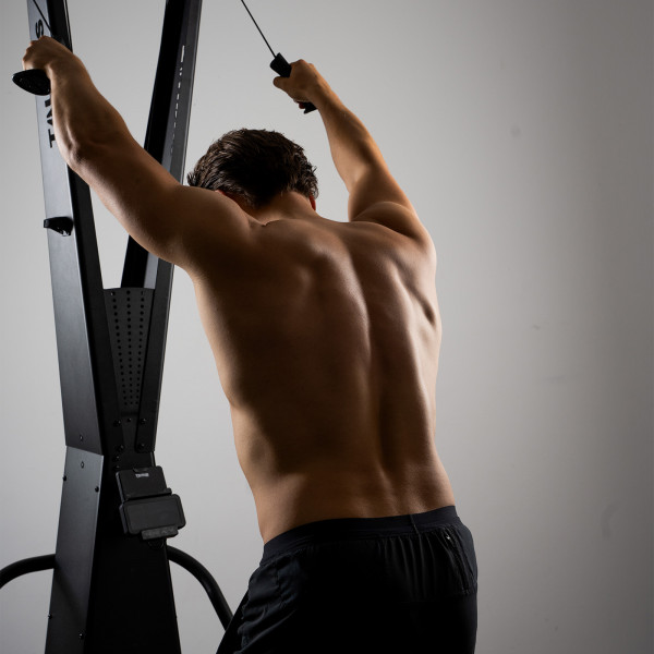 Model performing an overhead pull on the Taurus Elite Ski Trainer Pro