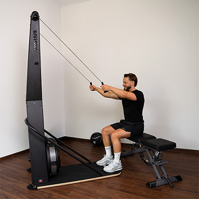 Model using the Taurus Elite Ski Trainer Pro while seated on a workout bench 