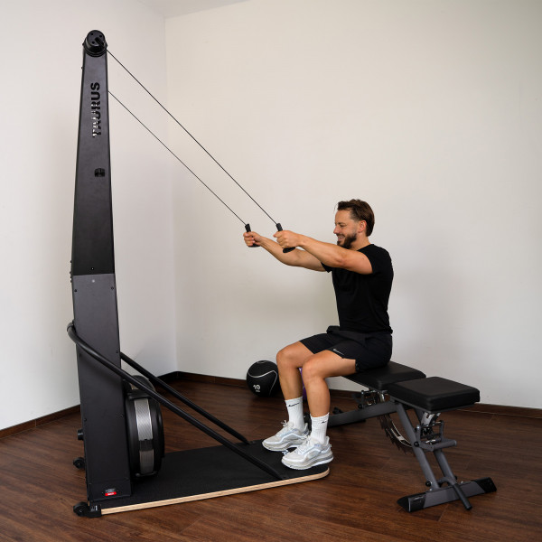 Model using the Taurus Elite Ski Trainer Pro while seated on a workout bench