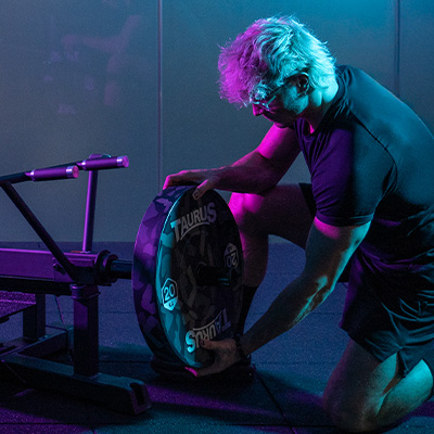 Model loading the Taurus Pro Iso T Bar Row with Olympic weights