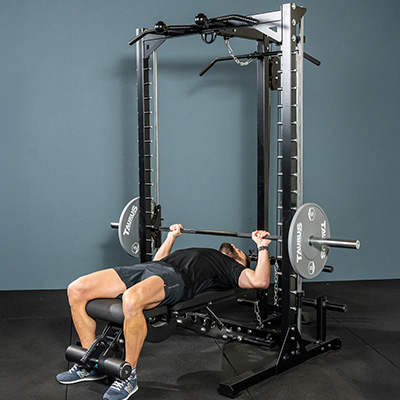 Person performing a bench press on the Taurus MS3 Pro Smith & Half Rack.