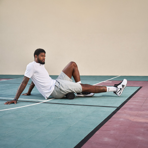 Applying the Theragun Wave Roller to the thighs for muscle recovery.