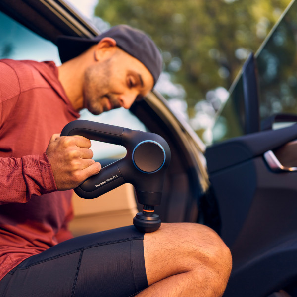 Lifestyle image of the Theragun Prime Plus being used by a model who is massaging their leg