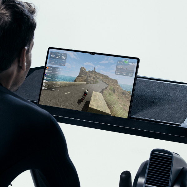 User cycling on the Wahoo KICKR Smart Bike V2, using a virtual cycling app on a tablet.