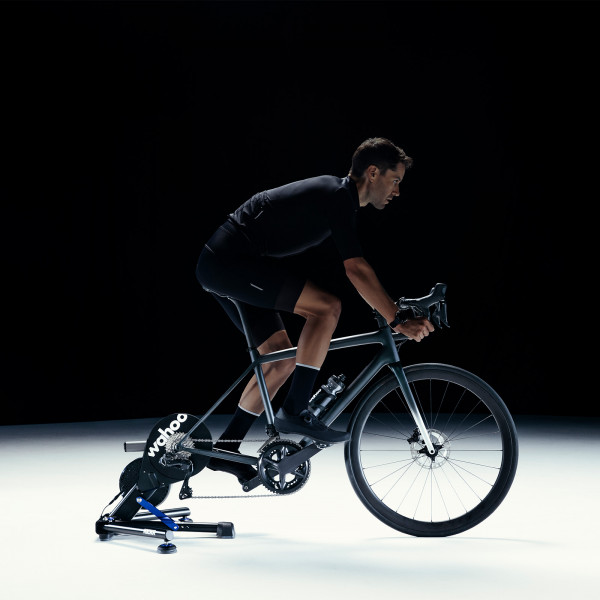 Cyclist riding the Wahoo KICKR V6 Smart Trainer in a dark studio setting.