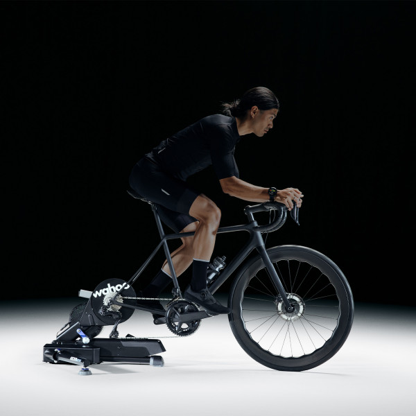 Cyclist riding the Wahoo KICKR MOVE Smart Trainer in a dark studio setting.