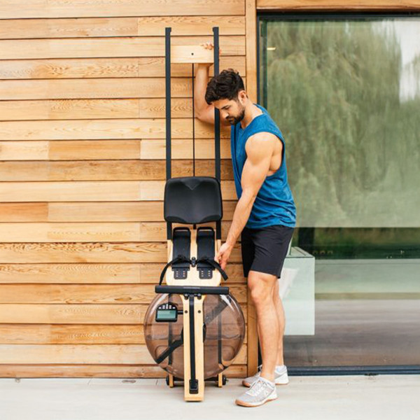 User storing the WaterRower Pure VR3 Oak Rowing Machine upright